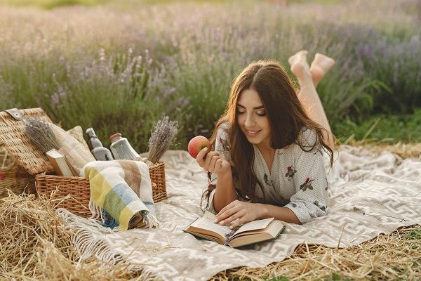 donna che legge un libro mentre mangia una frutta