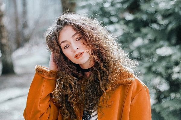 giovane donna che si stringe i capelli ricci e castani 