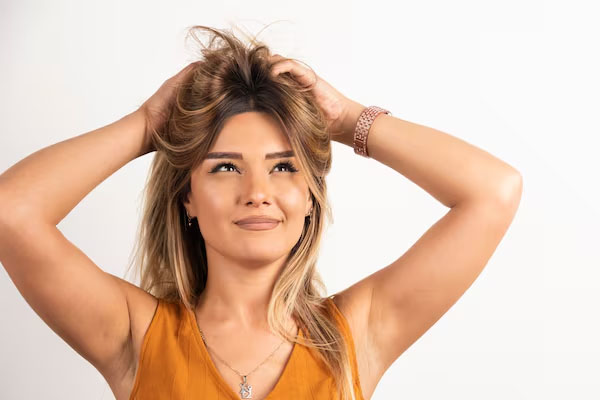Donna con un atteggiamento positivo che si tocca i capelli e posa su uno sfondo bianco