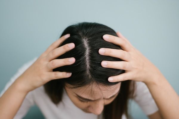 Primo piano della donna che mostra i capelli con le mani contro il muro