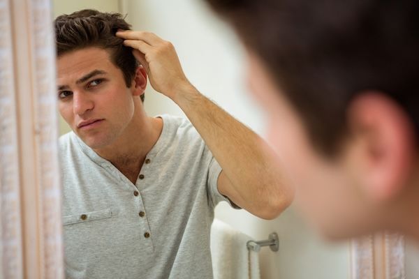 Uomo che si controlla i capelli allo specchio