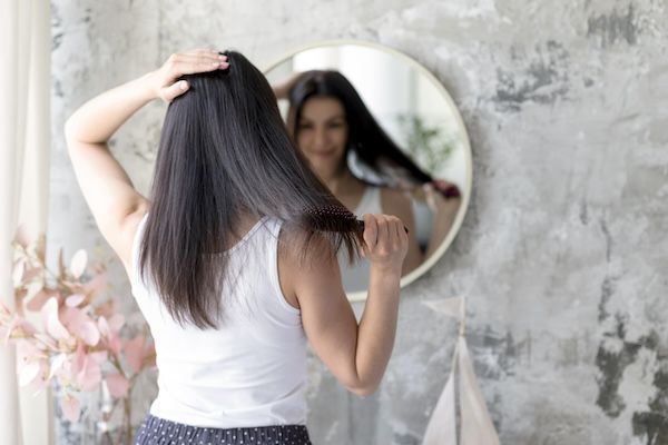 Donna abbastanza giovane che si spazzola i capelli