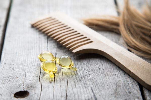 Nutrizione dei capelli. Capsula di siero vitaminico su fondo di legno.
