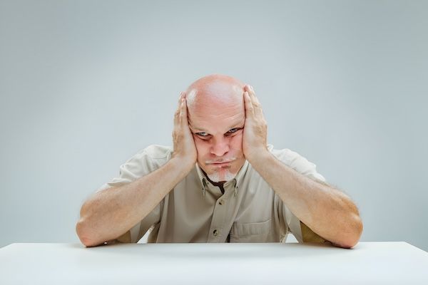 La postura frustrata dell'uomo con le mani sulla testa indica un periodo apparentemente interminabile di attesa