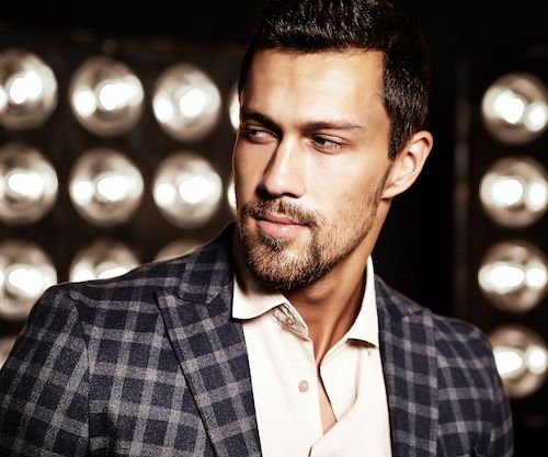 Ritratto di un uomo, modello maschile di moda, bello e sexy, vestito con un elegante abito su sfondo nero con luci da studio