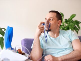 Un uomo malato di asma bronchiale respira attraverso una maschera per inalatore.