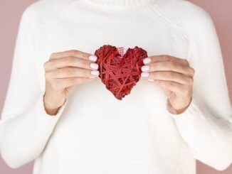 Mani che tengono vista frontale di una decorazione a forma di cuore