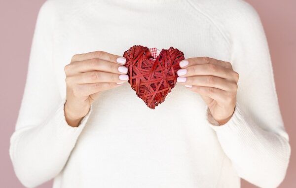 Mani che tengono vista frontale di una decorazione a forma di cuore