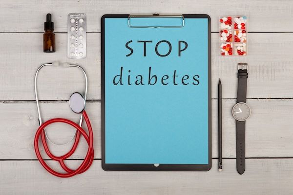 Clipboard con testo STOP diabete, stetoscopio, pillole, occhiali.