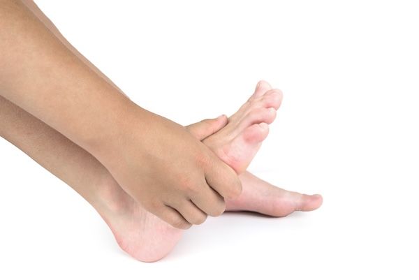 Dolore ai piedi: donna che soffre di dolore per un alluce valgo utilizza un massaggio manuale per rilassare i muscoli della pianta del piede
