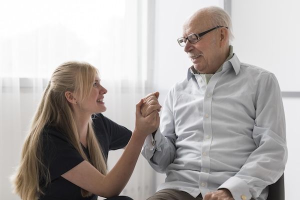 Uomo anziano che soffre di Alzheimer tiene la mano di un'infermiera