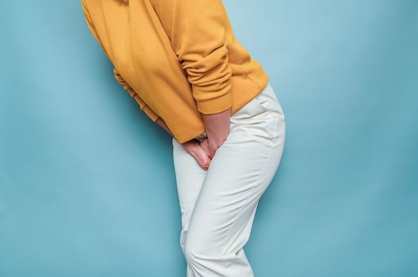 Sagoma di una donna con dolore alle urine e sintomi di clamidia Mani tra le gambe Salute della donna