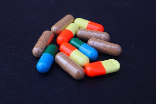 Un mucchio di pillole multicolori su uno sfondo nero.