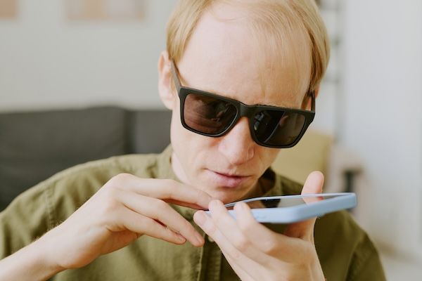 Primo piano medio di un uomo cieco da glaucoma che registra un messaggio vocale.