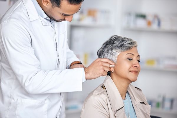 Apparecchio acustico medico e consulto con un medico e una donna con disabilità per tecnologia sanitaria e onde sonore. Medicina, benessere e audio con persone e impianto cocleare per trattamento contro la perdita d'udito improvviso