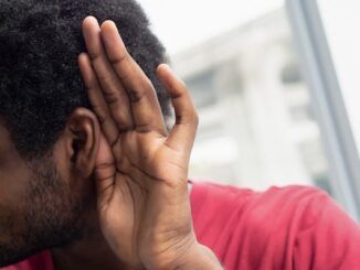 Triste, frustrato, infelice uomo nero africano che ascolta cattive notizie o ha una perdita di udito improvviso, concetto di farmaco per l'udito, apparecchio acustico, rumore, notizie false. Modello di uomo nero africano.