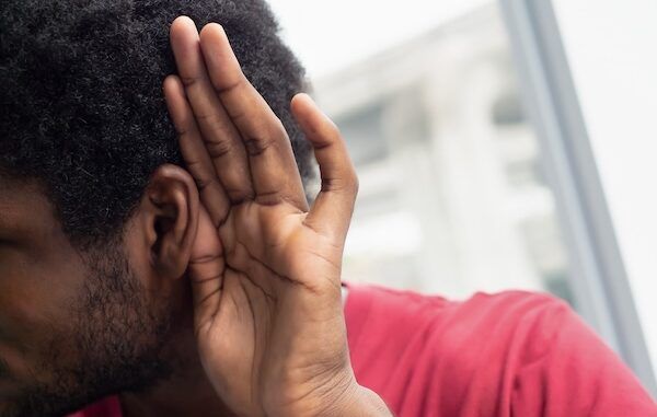 Triste, frustrato, infelice uomo nero africano che ascolta cattive notizie o ha una perdita di udito improvviso, concetto di farmaco per l'udito, apparecchio acustico, rumore, notizie false. Modello di uomo nero africano.