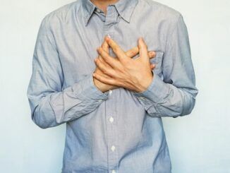 Un uomo adulto con sintomi di attacco cardiaco acuto ricorrente. Uomo che si tiene il cuore su uno sfondo blu. Dolore al petto. Angina pre-infarto, insufficienza cardiaca, angina, tachicardia, pericardite cos'è.