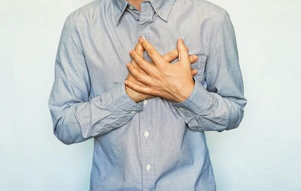 Un uomo adulto con sintomi di attacco cardiaco acuto ricorrente. Uomo che si tiene il cuore su uno sfondo blu. Dolore al petto. Angina pre-infarto, insufficienza cardiaca, angina, tachicardia, pericardite cos'è.