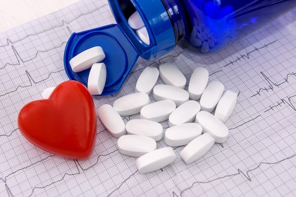 Bottiglia con pillole e siringhe su un cardiogramma, concetto di salute del cuore, pericardite cos'è