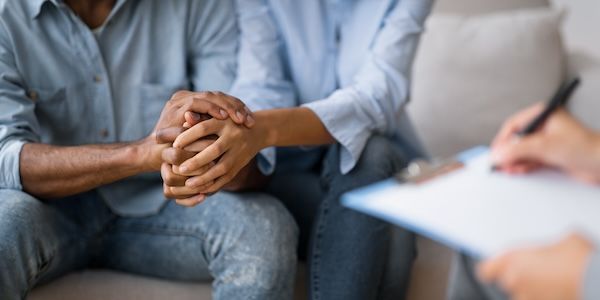 Concetto di terapia di coppia: uomo e donna neri irriconoscibili che si tengono per mano presso uno psicologo o uno psicoterapeuta.