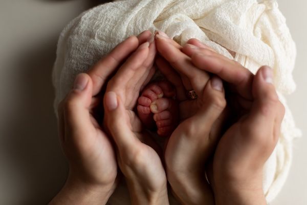 Mani di genitori che tengono i piedi del neonato.