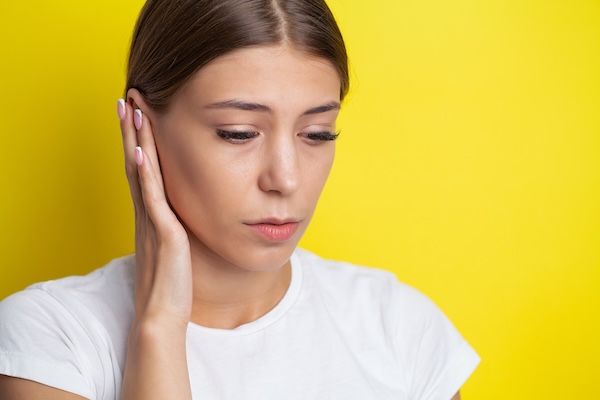 donna che si tocca l'orecchio a causa di un dolore sintomo dell'otite