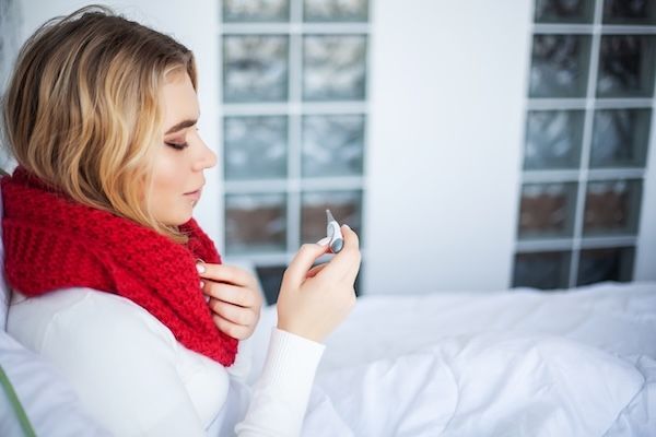 donna con febbre controlla il termometro cerca di fare abbassare la febbre alta