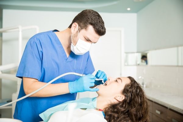 Giovane donna che riceve un trattamento dentale da un dentista uomo in clinica per prevenire l'ascesso gengivale che scoppia da solo