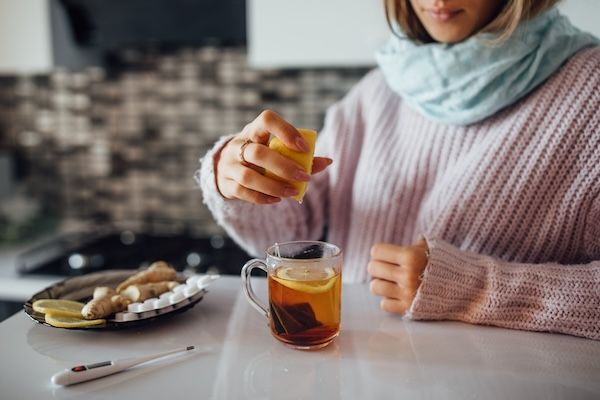 Mani femminili che spremono un limone nel tè per curare una bronchite senza febbre