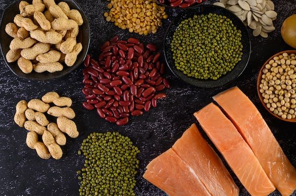 buone abitudini alimentari: Legumi e salmoni disposti su un pavimento di cemento nero.