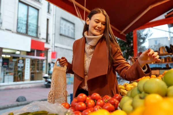 Una giovane donna di bell'aspetto in piedi davanti agli scaffali di frutta che compra alimentari in un mercato buone abitudini alimentari