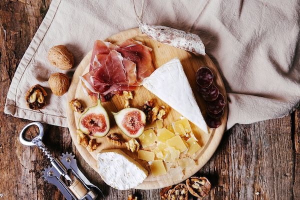 Deliziosi stuzzichini su tavola di legno con prosciutto salame noci