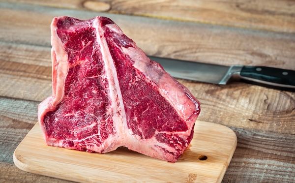 Costata di bue su tagliere di legno se mangiata in eccesso è uno dei cibi da evitare per il colesterolo alto