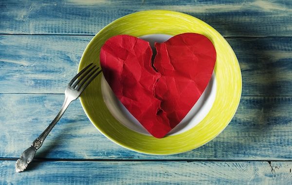 Vista dall'alto di un cuore spezzato di carta rossa su un piatto, appoggiato su un tavolo, concetto di alimentazione salutare per abbassare il colesterolo HDL