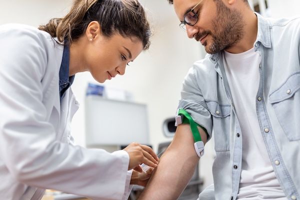 Gentile infermiera dell'ospedale che raccoglie campioni di sangue dal paziente in laboratorio per controllare i livelli di colesterolo HDL