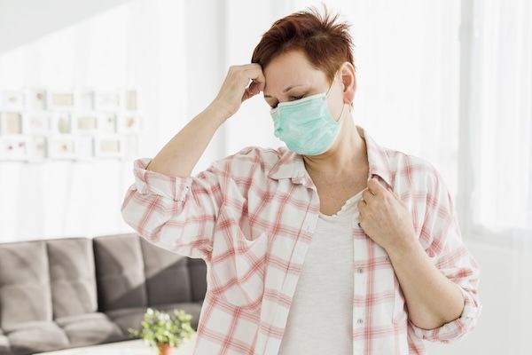 Vista frontale di un'anziana che indossa una mascherina medica a causa del covid eg.5 sintomi