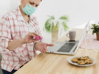 Vista laterale dell'anziana che disinfetta le mani prima di usare il computer portatile per prevenire il covid eg 5 e sintomi