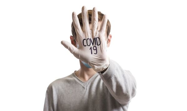 Palmo con guanto medico sul viso con la sigla COVID eg 5 sintomi