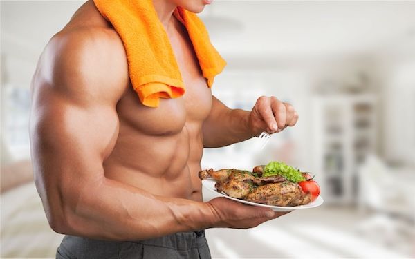 giovane uomo muscoloso che mangia salutare pollo e pomodori per una dieta aumentare massa muscolare senza ingrassare