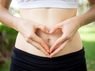 Primo piano, donna, mani, formano un cuore sul ventre. concetto di motilità intestinale salutare