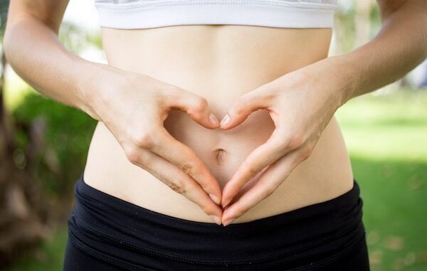 Primo piano, donna, mani, formano un cuore sul ventre. concetto di motilità intestinale salutare