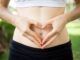 Primo piano, donna, mani, formano un cuore sul ventre. concetto di motilità intestinale salutare