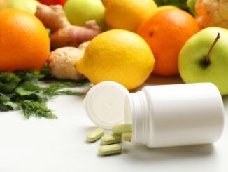 "Integratori alimentari in bottiglie di plastica e prodotti su tavolo bianco per capire a cosa servono vitamine e minerali