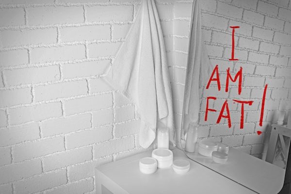 Testo "Sono grasso" scritto sullo specchio del bagno tra le cause dell'anoressia c'è l'impossibilità di vedere la realtà per quella che è