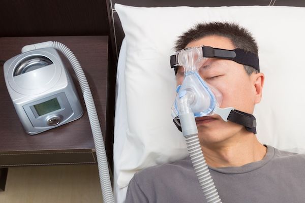"Uomo asiatico con apnea notturna che usa la macchina CPAP