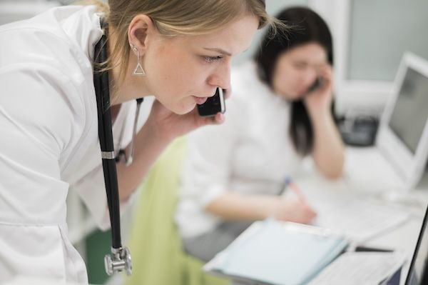 Dottore che parla al telefono con altri colleghi dato che la bulimia nervosa richiede un approccio multidisciplinare