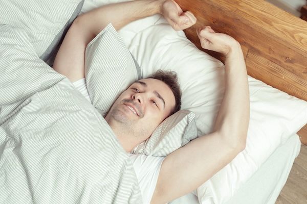 uomo che si è appena svegliato felice perché ha dormito bene e sa che la dieta non è l'unico modo per abbassare il colesterolo alto