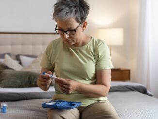 Donna diabetica di mezza età che controlla il suo livello di glucosio per via della differenza diabete 1 e 2