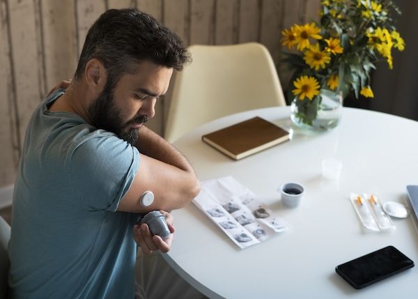 Uomo diabetico che controlla il sensore del cerotto per la glicemia e differenza tra diabete 1 e 2 